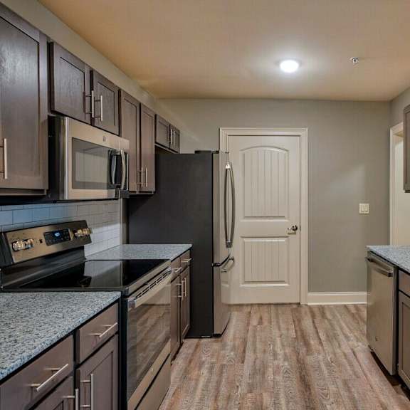 Thumbnail 5 of 5 A kitchen with dark brown cabinets and a black refrigerator at Mode at Melbourne, LLC Apartments, Florida, 32901