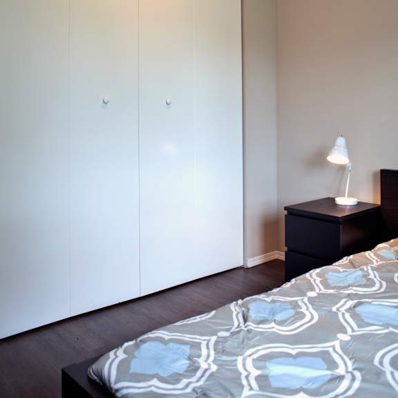 a bedroom with a bed, nightstand, and wardrobe.