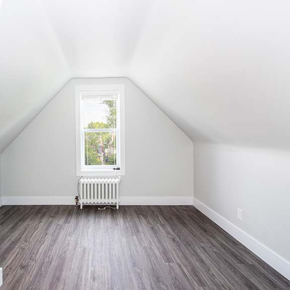 a small attic room with a window and a radiator