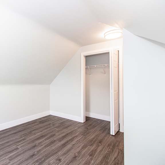 a bedroom with hardwood floors and white walls