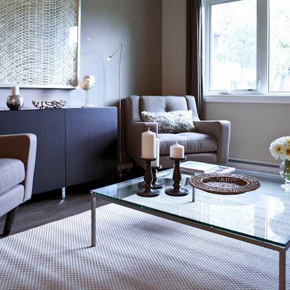 a living room with a glass coffee table and a grey sofa.