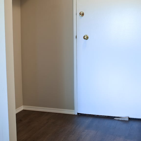 a white door with a gold handle is in a room with a wood floor.