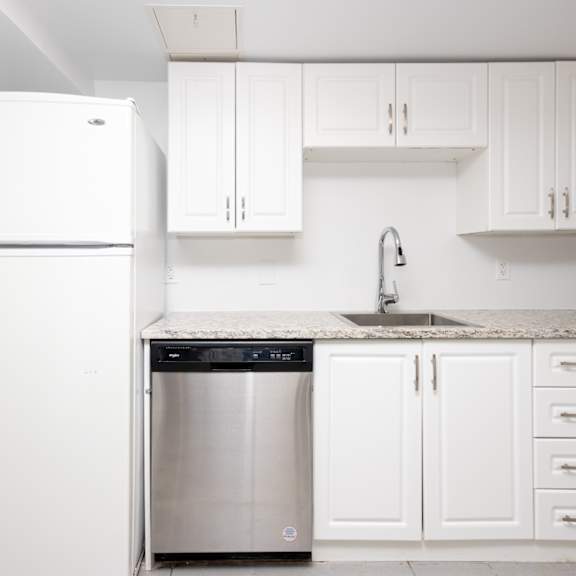 a white kitchen with a dishwasher and fridge.