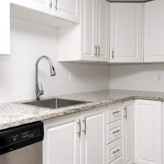 a kitchen with white cabinets and a granite countertop.