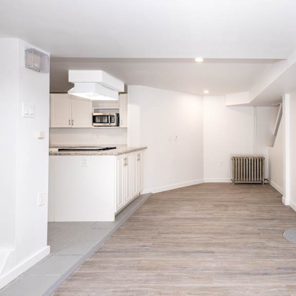 a spacious kitchen with white cabinets and a wooden floor.