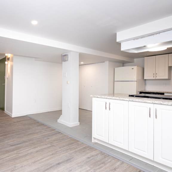 a white kitchen with wooden floors and white cabinets.