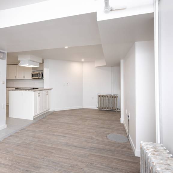 a spacious kitchen with white cabinets and a wooden floor.