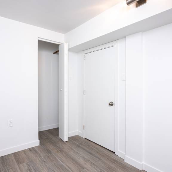 a white door is on the right side of a room with a wooden floor.