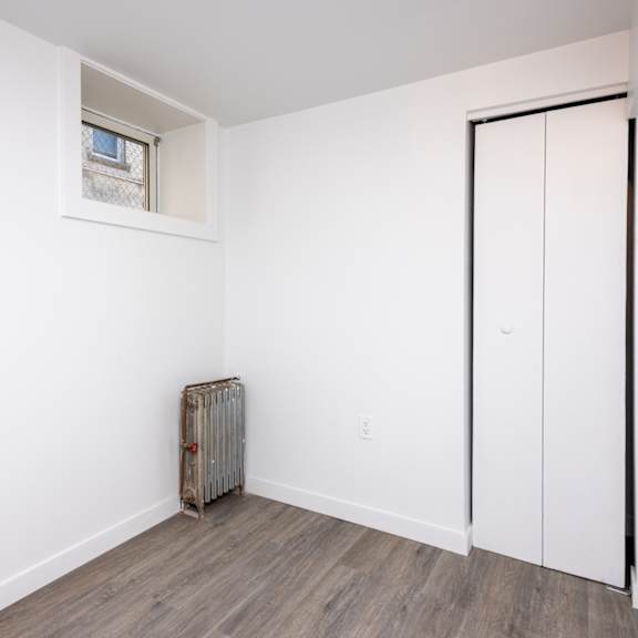 a room with a window, a radiator, and a door.