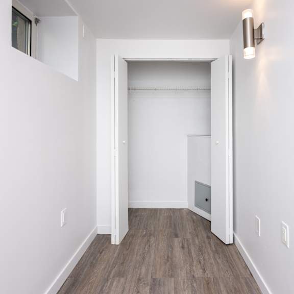 a white door is open to a room with wood flooring.