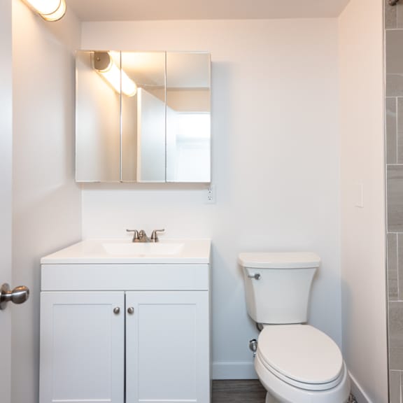 a white bathroom with a toilet, sink, and medicine cabinet.
