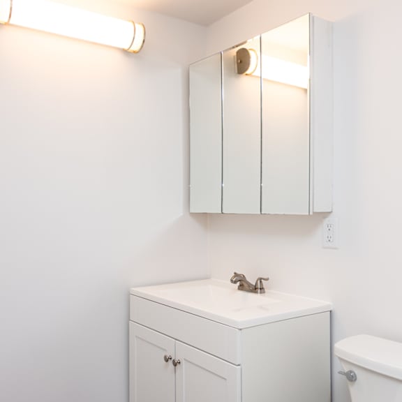 a white bathroom with a toilet, sink, and medicine cabinet.