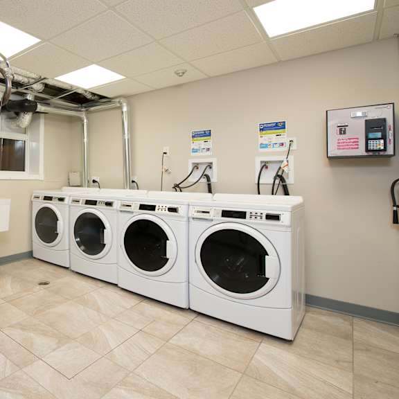 a row of white front load washing machines in a laundromat.