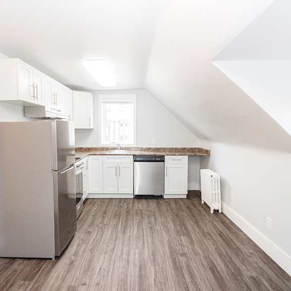 a small kitchen with white cabinets and a stainless steel refrigerator