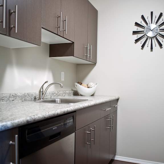 a modern kitchen with dark wood cabinets and stainless steel appliances.