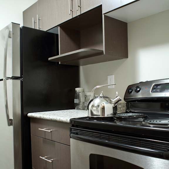 a modern kitchen with a black refrigerator, stainless steel oven, and a white countertop.
