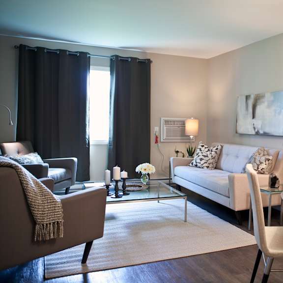 a modern living room with a grey sofa, a glass coffee table, and a large painting on the wall.