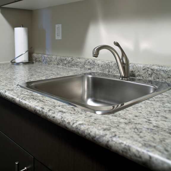 a modern kitchen with a stainless steel sink and dark cabinets.