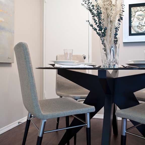 a dining table with chairs and a vase of flowers.