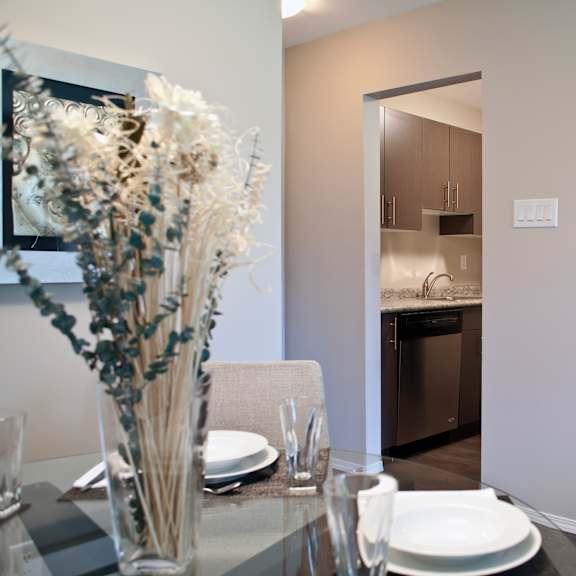 a dining table with a vase of flowers and plates on it.