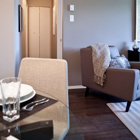 a modern living room with a grey couch, a glass table, and a white chair.