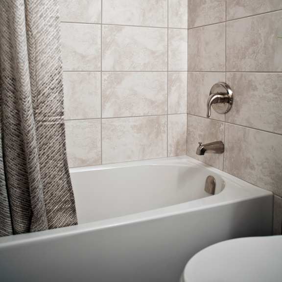 a white bathtub with a shower curtain and a shower head.