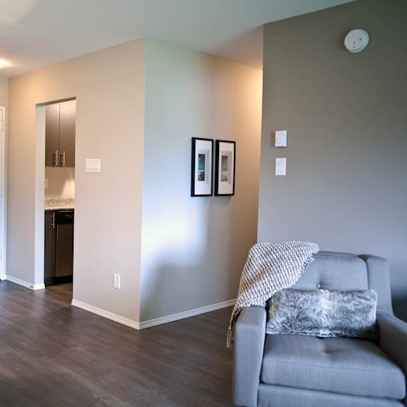 a grey couch with a white blanket is in the corner of a room with a dining table and chairs.