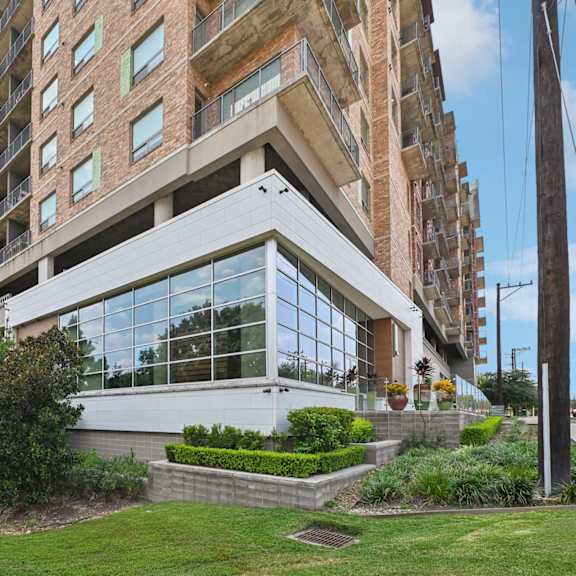 a modern building with a large glass facade and a landscaped front yard.