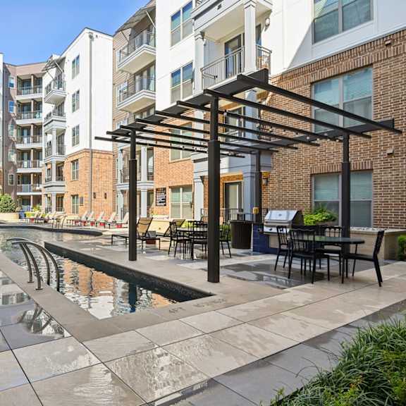 a modern outdoor pool area with a water feature and seating area.