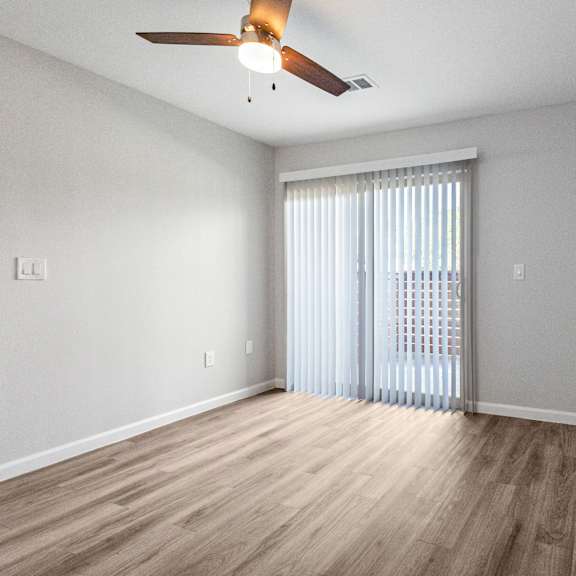 a room with a ceiling fan and sliding glass doors.
