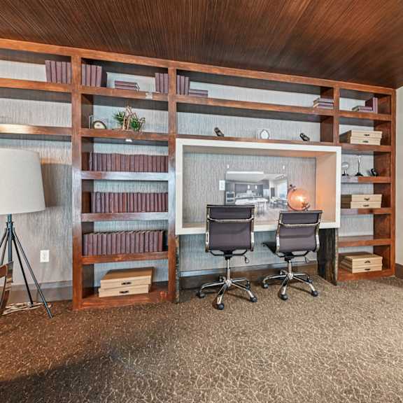 a room with a desk, chairs, and shelves filled with books.