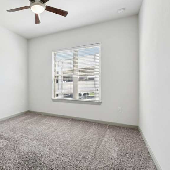 a room with a ceiling fan and a window with blinds.