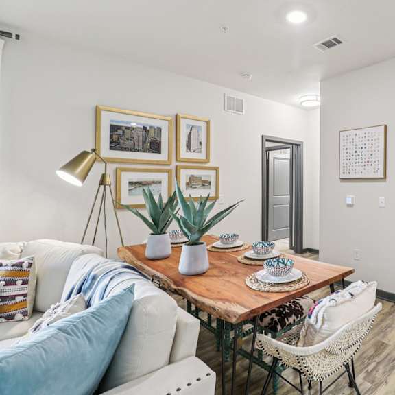 a living room with a white couch, a wooden table, and a white chair.