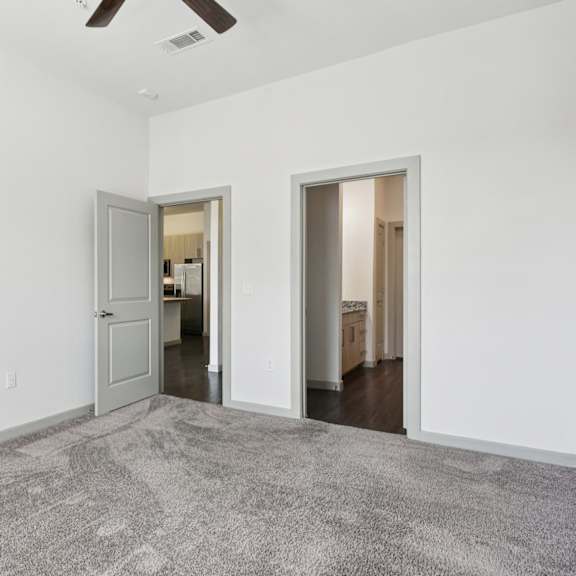 a room with a grey carpet and a ceiling fan.