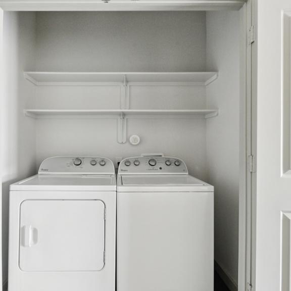 a white washing machine and dryer in a white cabinet.