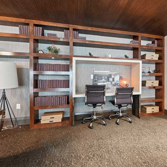 a business center with a desk, chairs, and shelves filled with books.