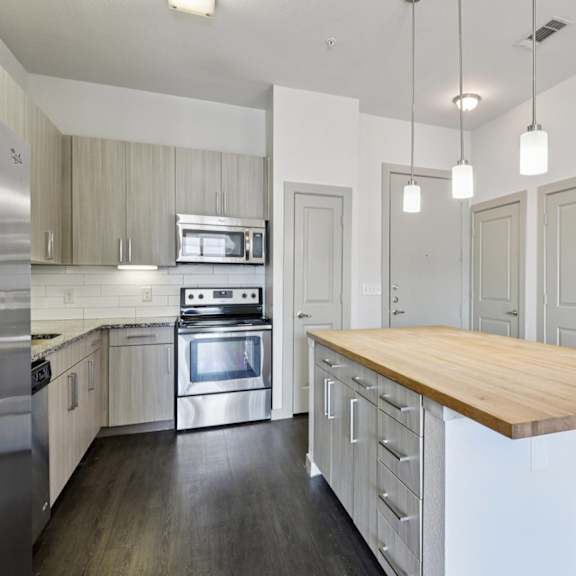a kitchen with a wooden counter top and stainless steel appliances.