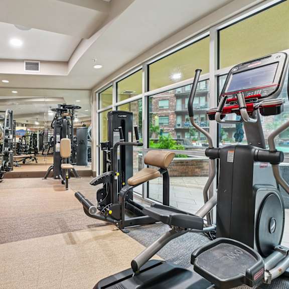 a gym with a variety of cardio equipment including treadmills, weights, and exercise machines.
