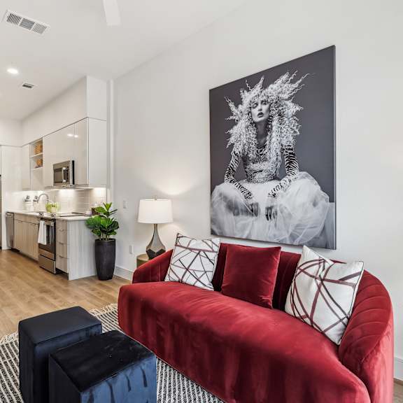 a living room with a red couch and a large black and white painting on the wall.