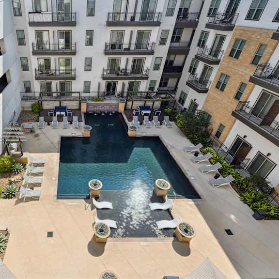 a pool surrounded by patio furniture and concrete pillars.