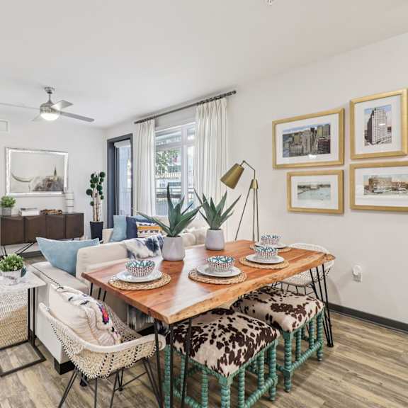 a dining area with a table set for two and a couch with a throw pillow.