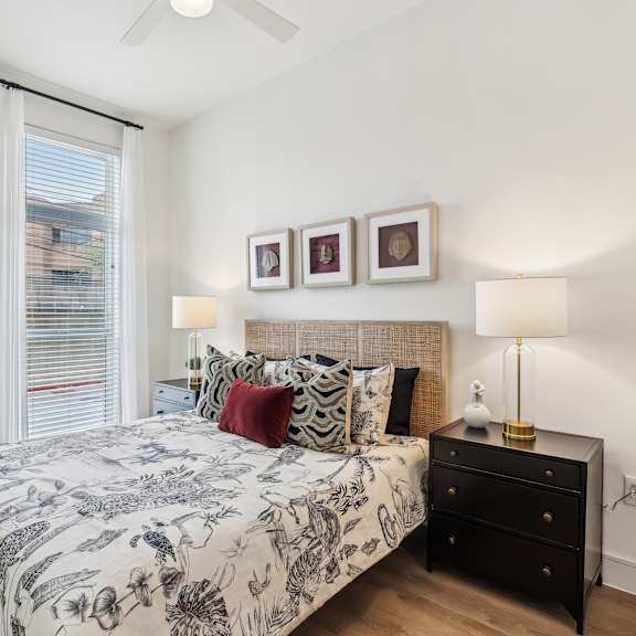 a bedroom with a bed, nightstand, and a plant.