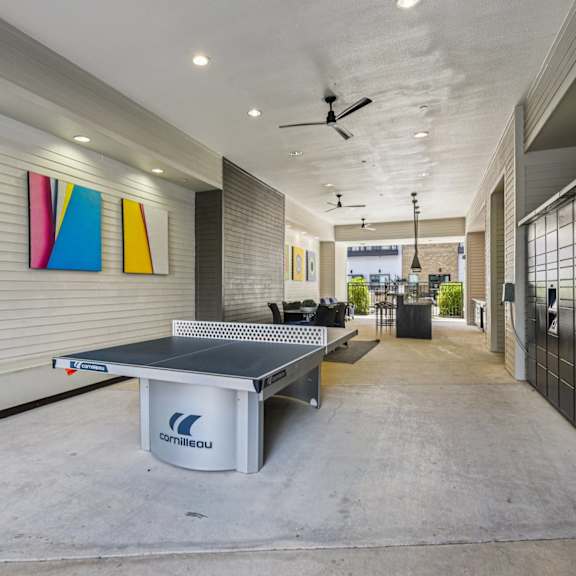 a ping pong table is in the middle of a room with a ceiling fan.