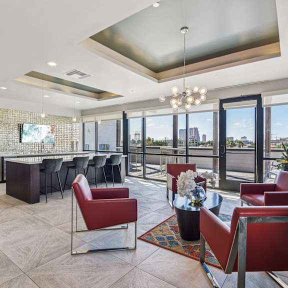 a modern living room with a glass table and red chairs.