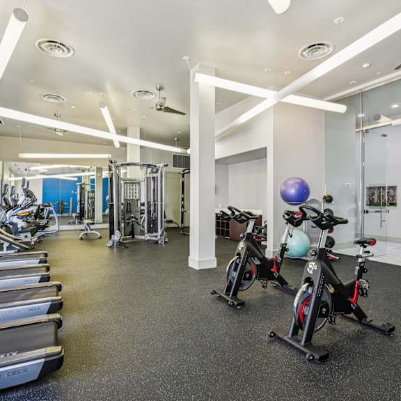 a gym with treadmills, exercise bikes, and a mirror.
