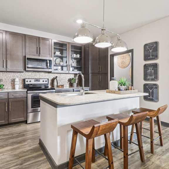 a kitchen with a white island and wooden bar stools.