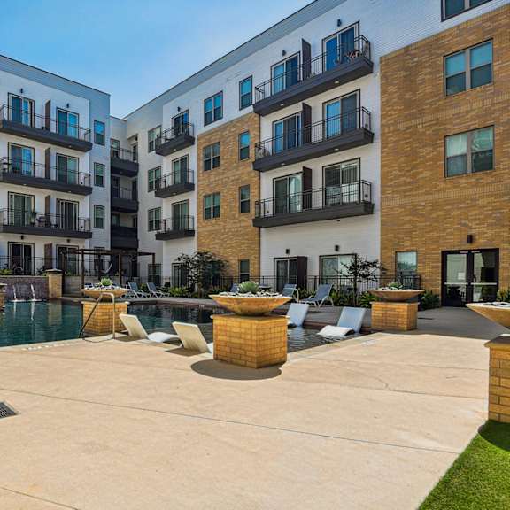 a modern apartment complex with a pool and outdoor seating area.