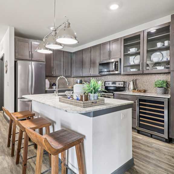 a kitchen with a white island and dark brown cabinets.