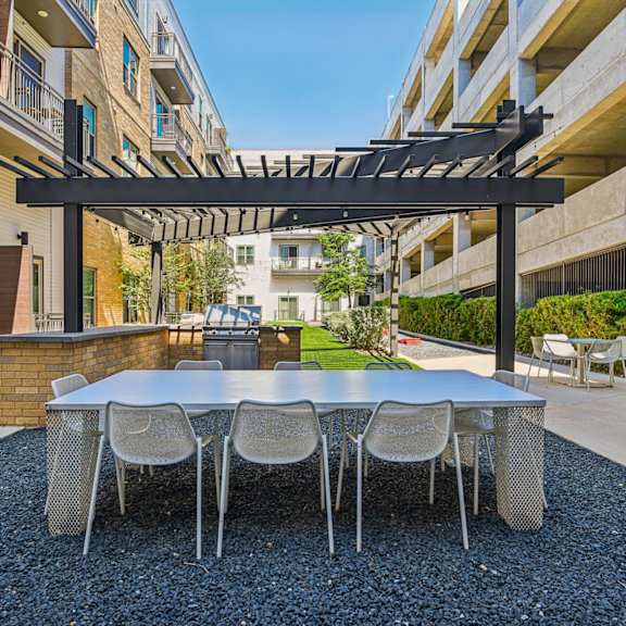 a patio with a table and chairs under a pergola.