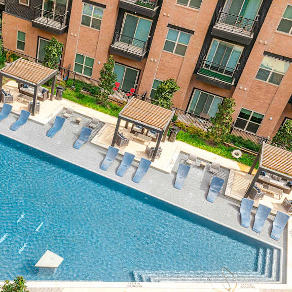 a swimming pool surrounded by sun loungers and a building in the background.